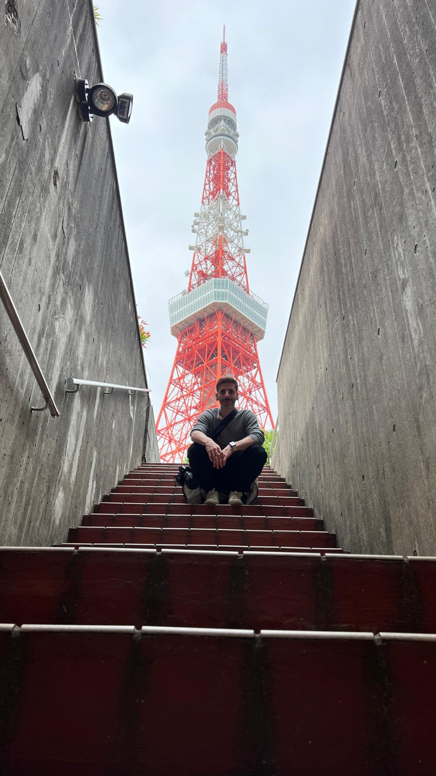 Carlos sentado en unas escaleras con Tokyo Tower al fondo en Tokio