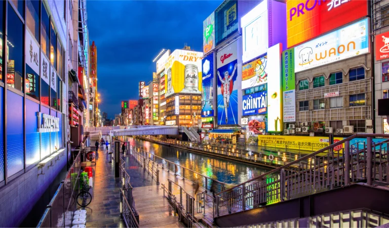 Canal de Dotonbori en Osaka de noche con carteles luminosos y ambiente urbano en Japón