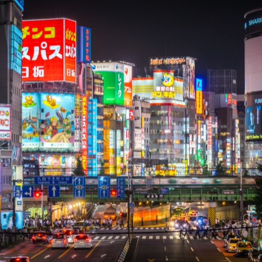 Avenida de Tokio de noche con tráfico, pantallas luminosas y edificios llenos de carteles