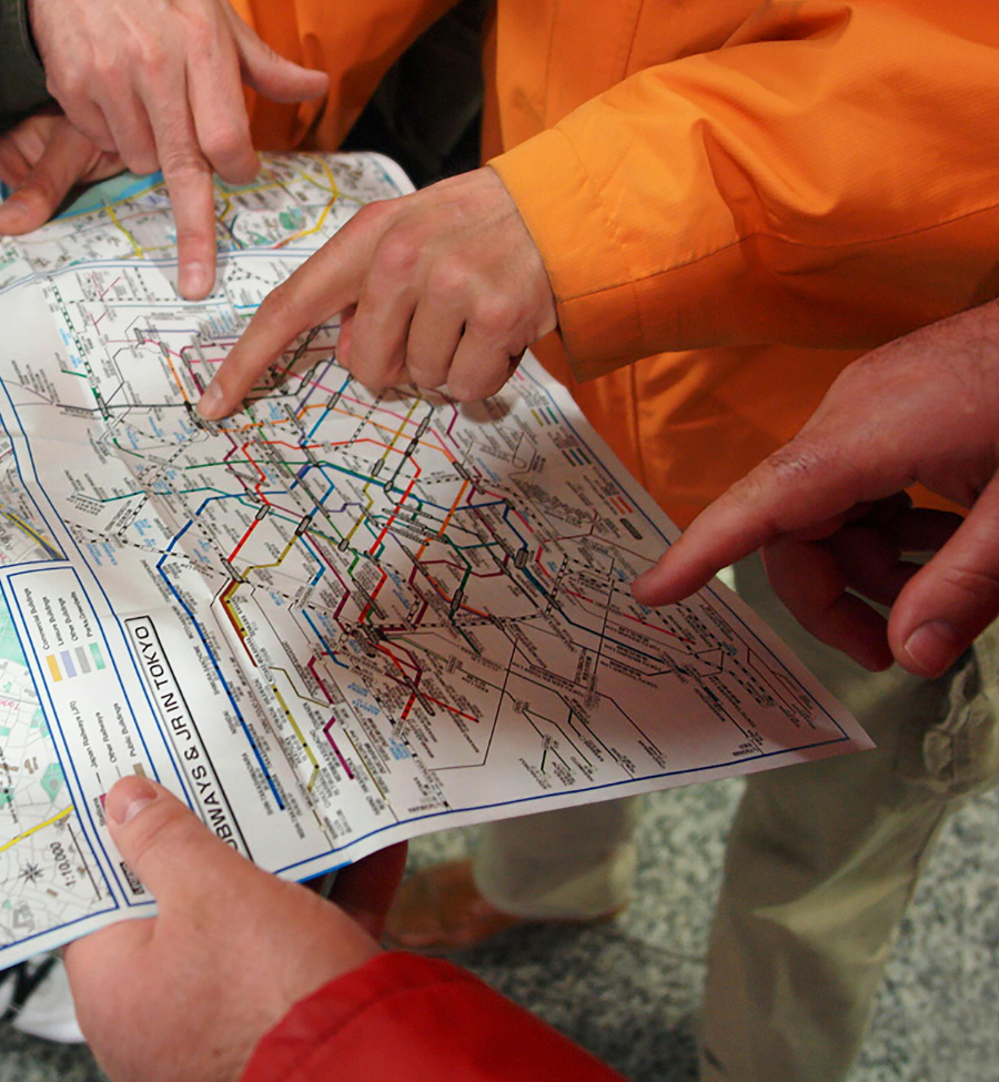 Personas consultando un mapa de trenes y metro durante un viaje por Japón.