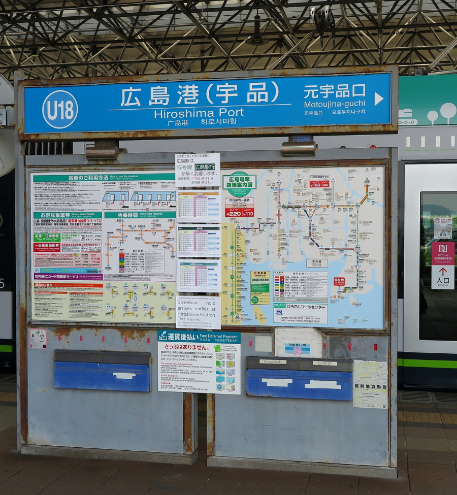 Señal de Hiroshima Port, Ujina, en una parada de tranvía de Hiroshima con mapas e información de transporte.